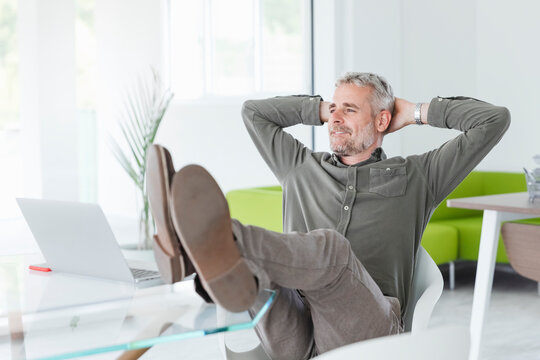 Relaxed businessman contemplating at desk in office