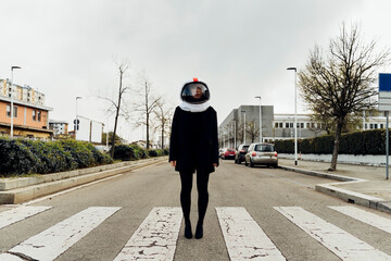 Woman with space helmet standing on zebra crossing at street