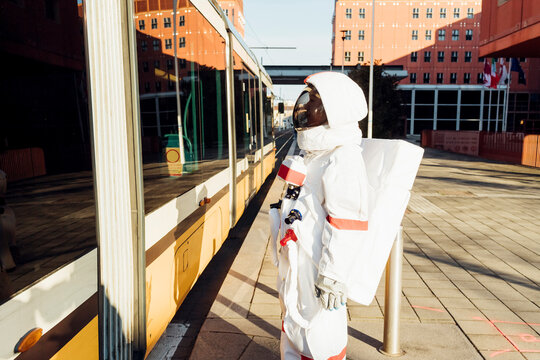 Female astronaut standing near tram at station in city