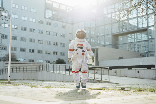 Female astronaut in mid-air on footpath during sunny day