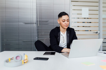 Female professional using laptop while working at office