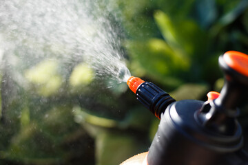 Close-up manual garden hand compression sprayer with pump. Spraying water in the garden. Farmer...