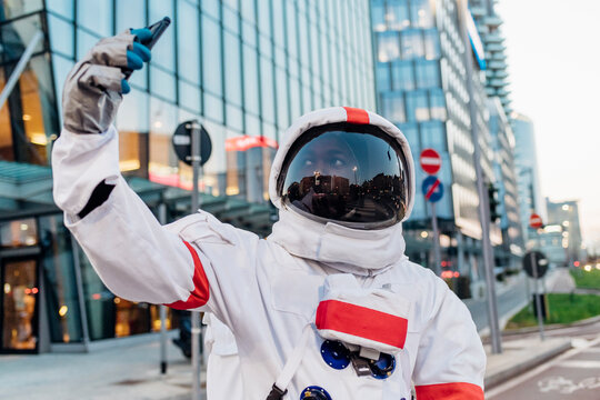 Male astronaut taking selfie through smart phone in city