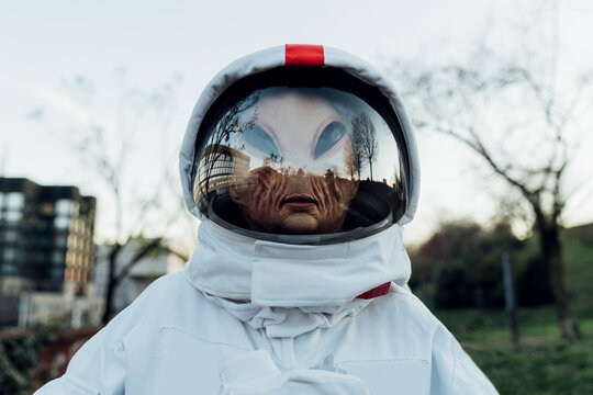 Woman astronaut with alien mask standing outdoors