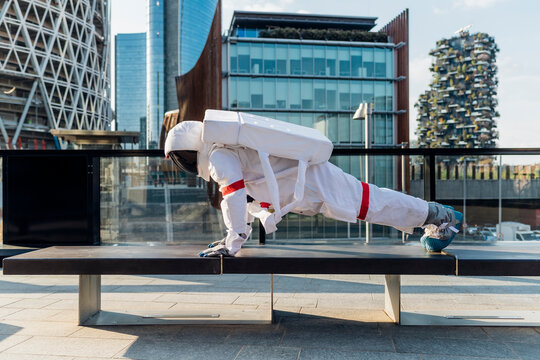Male astronaut wearing space suit doing push-ups on bench