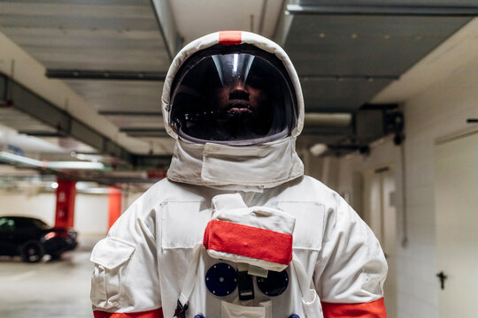 Mid adult astronaut wearing space helmet standing in parking lot