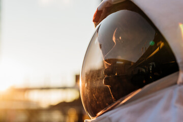 Mid adult astronaut wearing space helmet looking away during sunset