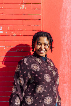 Woman smiling while standing in front of red wall