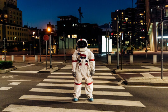 Male astronaut standing on zebra crossing during night