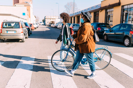 Female friends with bicycle crossing road in city