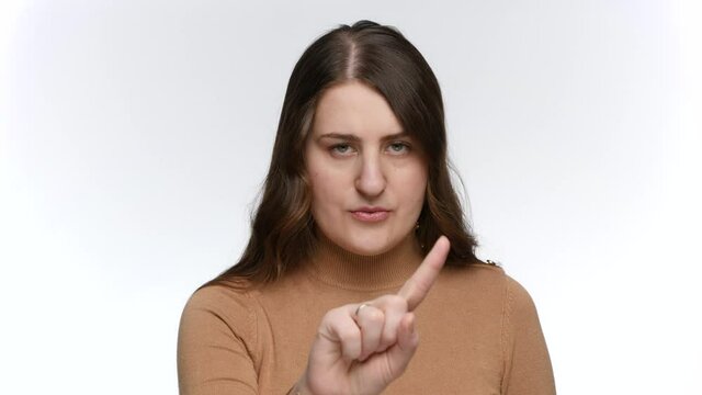 Portrait of young woman saying no by shaking index finger. Concept of ban, prohibition and taboo.