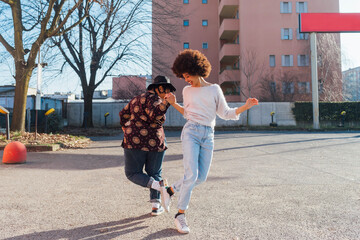 Cheerful women greeting through foot bumps on footpath