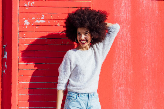 Smiling young woman standing with hand in hair during sunny day