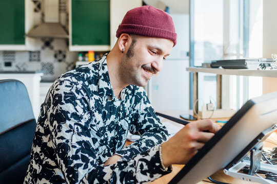 Smiling man using graphics tablet at home