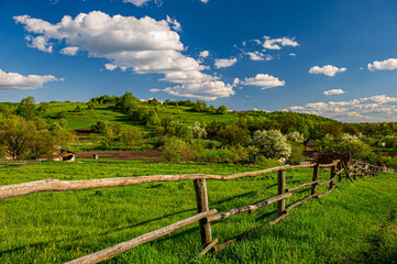wooden fence on a meadow in a hilly area on a sunny day, rural landscape.