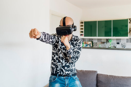 Young man wearing virtual reality simulator punching at home