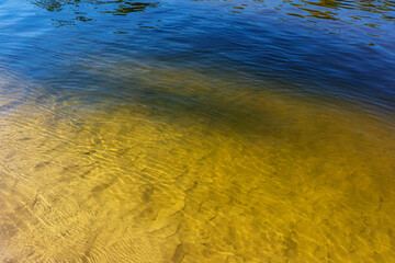 Reflection of trees on the surface of the water in the river and the sandy bottom.