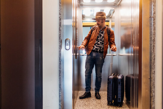 Man in hat pushing button in elevator