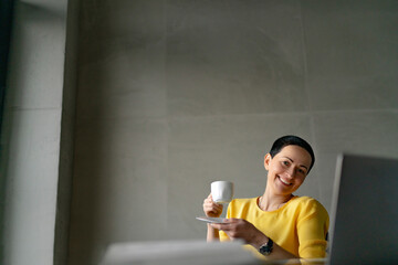 Smiling female professional having coffee in office