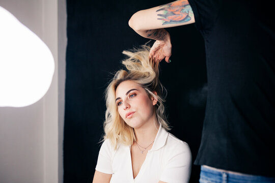 Female hairdresser styling hair of model in studio