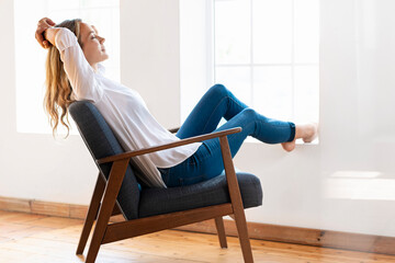 Woman with eyes closed relaxing on chair at home