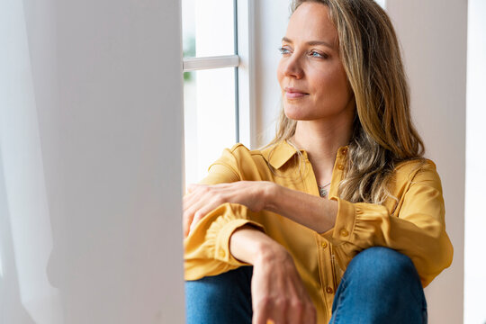 Woman day dreaming while sitting at window