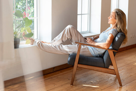 Woman with coffee mug relaxing on chair at home
