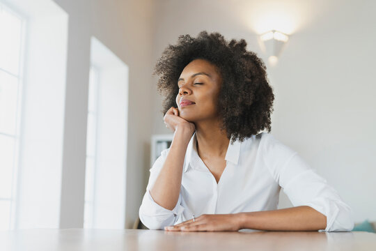 Young woman with hand on chin day dreaming at home