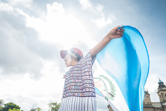 Portrait of a girl screaming at the sky, holding a flag in the backlight.