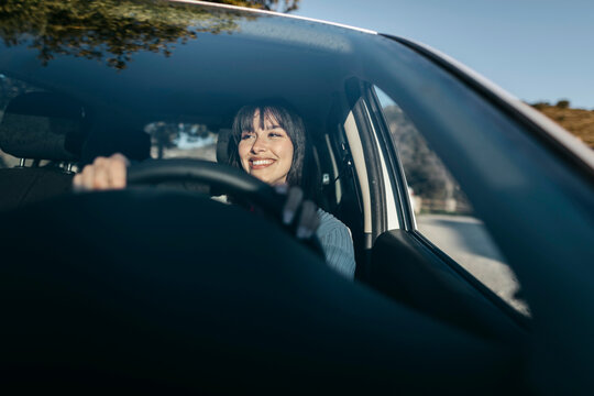 Young woman driving car seen through windshield