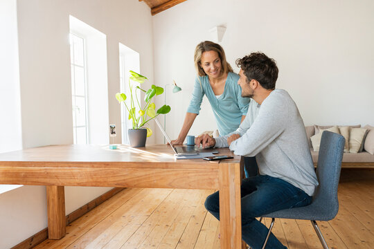 Man sitting at desk with laptop looking at girlfriend at home office