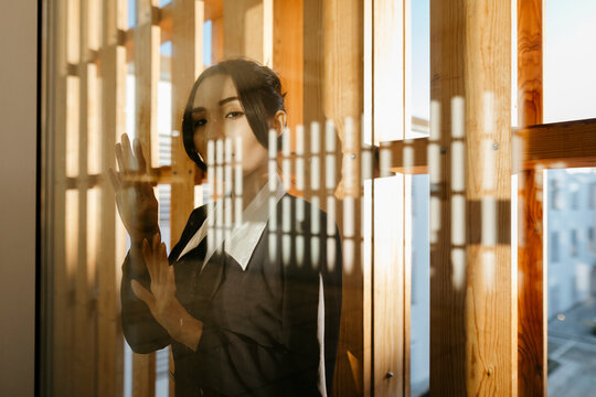 Young woman looking through window glass