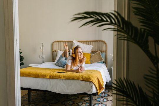 Young woman looking away while relaxing on bed at home