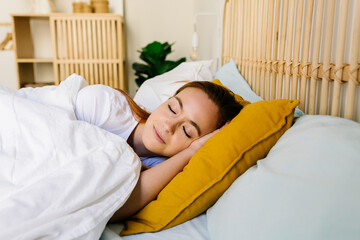Beautiful woman with eyes closed asleep in bed at home
