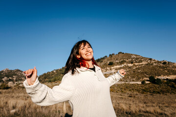 Smiling woman with arms outstretched on mountain