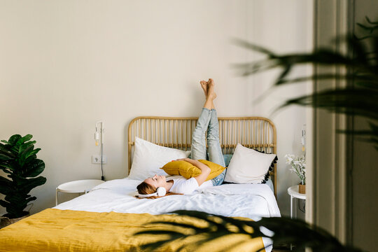 Young woman listening music while lying on bed at home