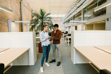 Male and female professionals working with digital tablet at coworking office