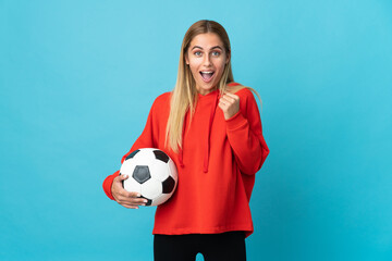 Young football player woman isolated on blue background celebrating a victory in winner position