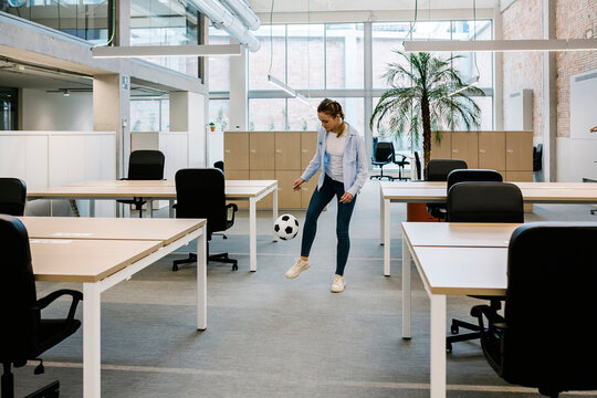 Businesswoman playing with soccer ball at coworking office