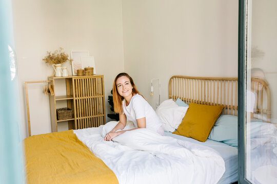 Woman looking away while relaxing on bed at home