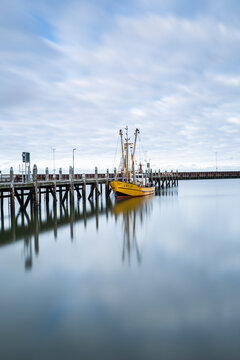 Denmark, Romo, Clouds over fishing boat moored to wooden pier