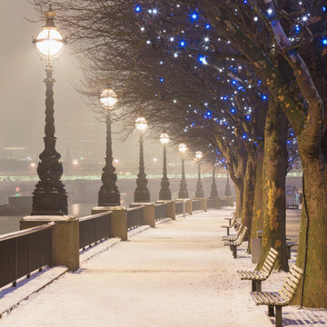 UK, England, London, Row of street lights illuminating empty snow-covered promenade