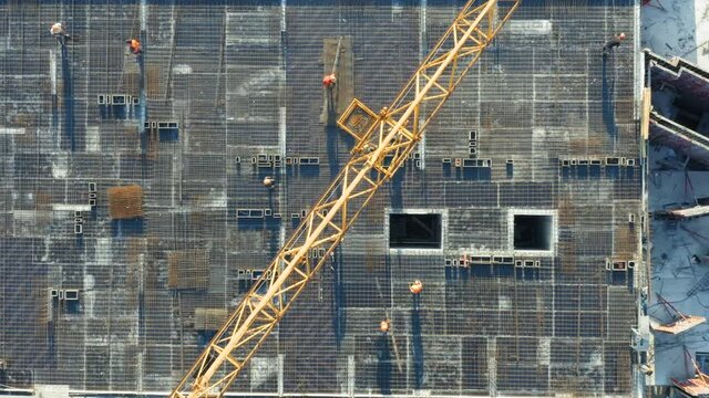 Aerial top down view on the rooftop of an apartment building under construction with a lot of workers laying rebar