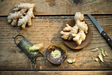 Kitchen knife, ginger roots and old grater lying on wooden surface