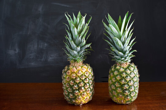 Still life with two pineapples in front of dark wall