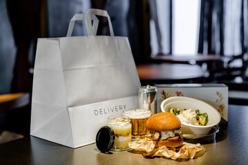 Meal with drink, dessert and salad by delivery bag and box on kitchen island