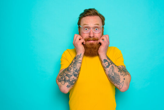 Man with yellow t-shirt and beard is shocked about something
