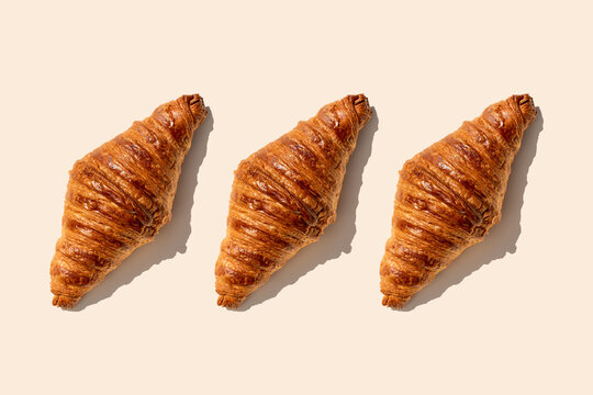 Butter croissants in a row on beige background