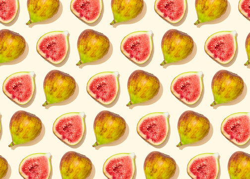 Pattern of halved figs flat laid against light yellow background