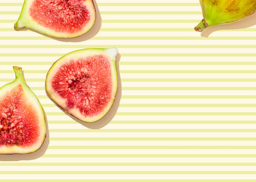 Studio shot of halved figs lying against yellow striped background